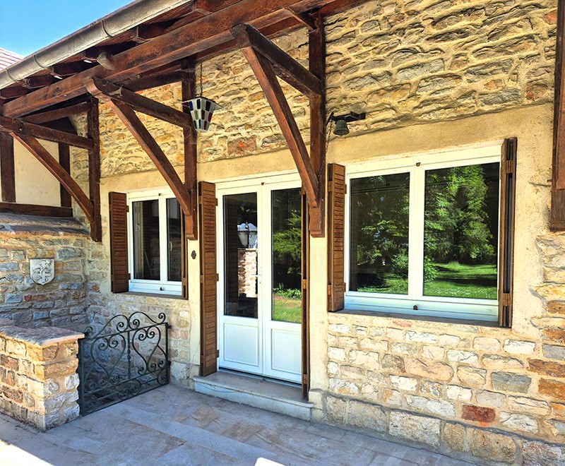 Maison de campagne avec fenêtres et porte d'entrée en PVC blanche.