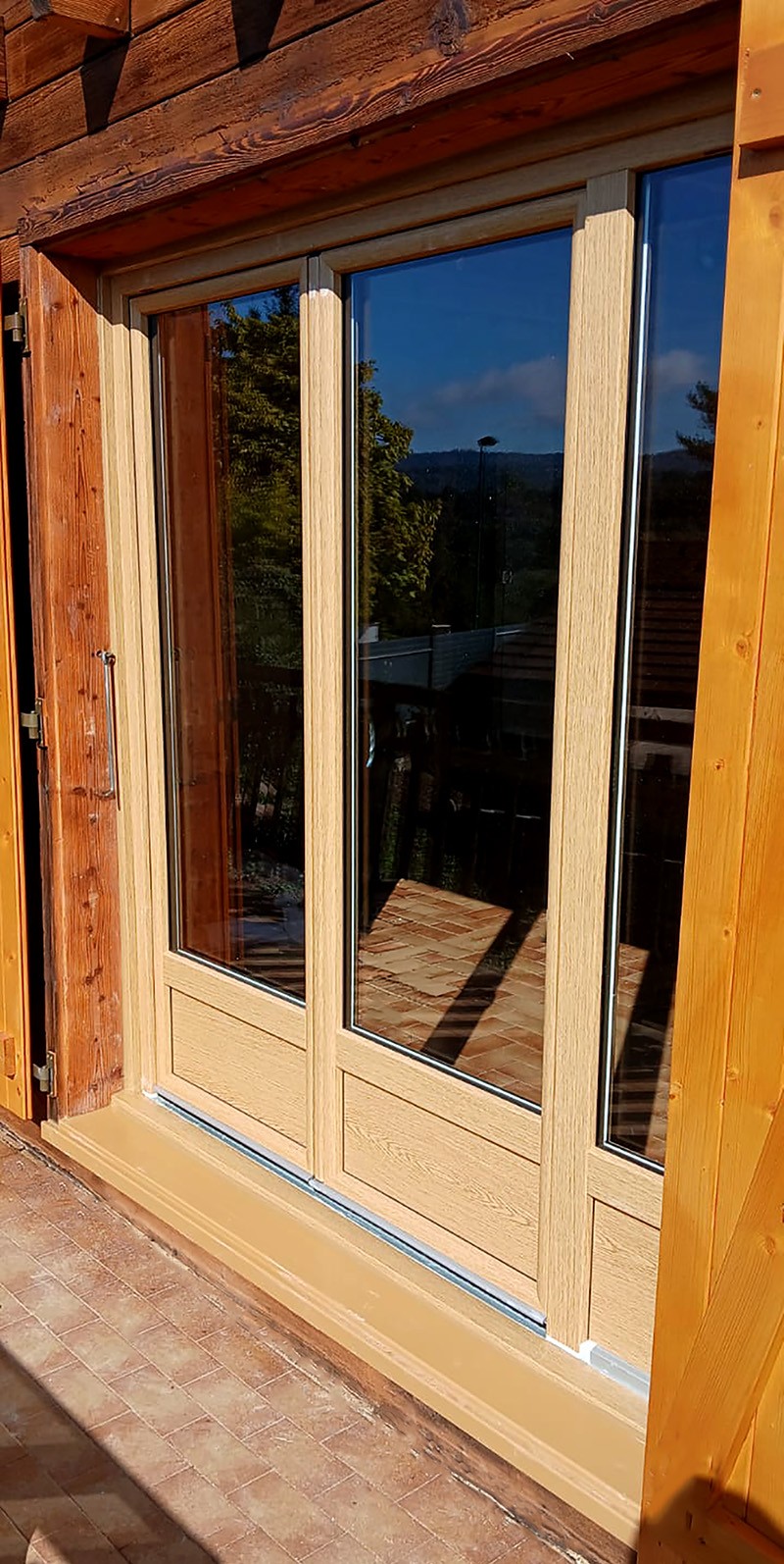 Porte-fenêtre en PVC teinte "Coriander oak" gamme INO'80 dans un esprit chalet de montagne